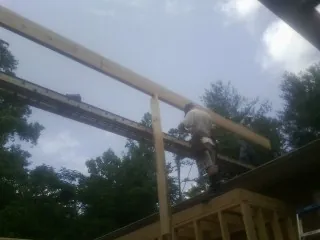 Carpenter setting a ridge beam over a new addition frame — Ice Dam Removal by Roofing Brothers in Saint Peter