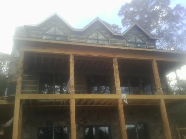 Dormers and porch framing on a large log home under construction — Roof Coating work by our crew in Saint Peter