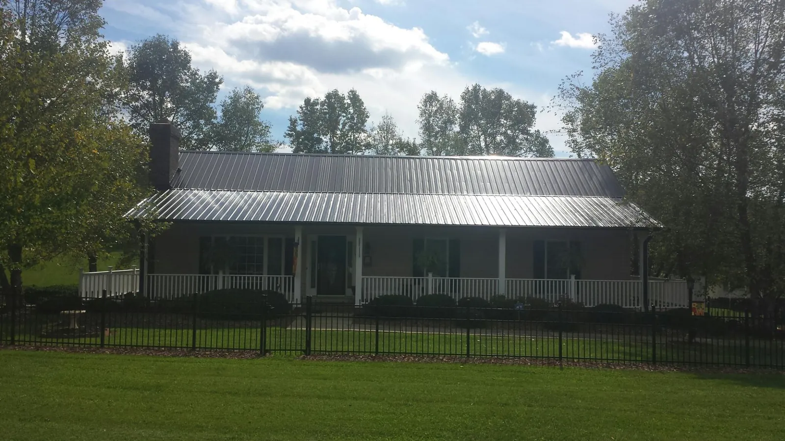 Gray metal roof on a brick ranch with a full width front porch — Gutter Guard Installation work by our crew in Saint Peter