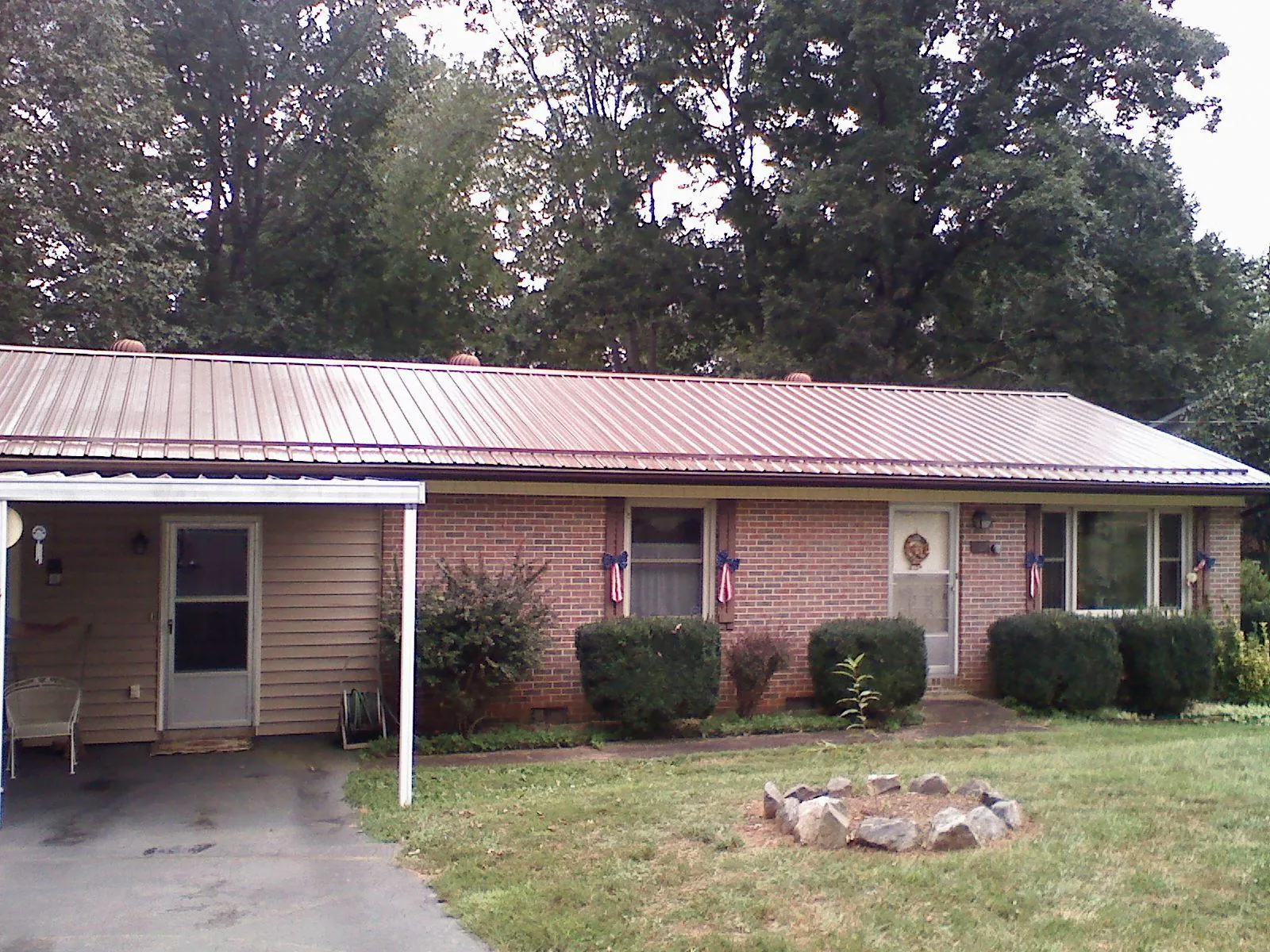 Bronze metal roof and carport on a brick ranch home — Roof Repair work by our crew in Saint Peter